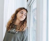 εφηβική κατάθλιψη κοπέλα κάθεται στο παράθυρο και κοιτάει