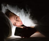 Αϋπνία γυναίκα είναι στο σκοτάδι με το κινητό της