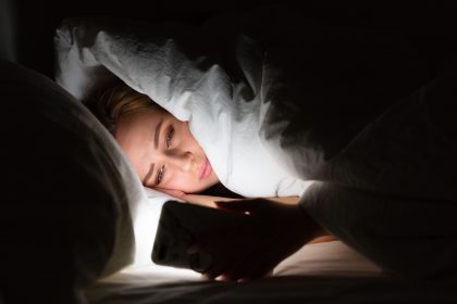 Αϋπνία γυναίκα είναι στο σκοτάδι με το κινητό της