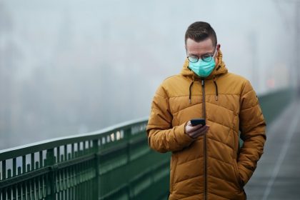 άνδρας με μάσκα σε κακοκαιρία και άνοδο των κρουσματων