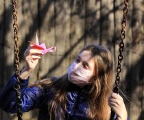 κοριτσάκι κρατάει χάρτινο οριγκάμι και κάνει κούνια