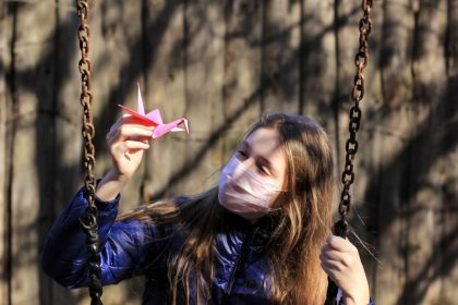 κοριτσάκι κρατάει χάρτινο οριγκάμι και κάνει κούνια