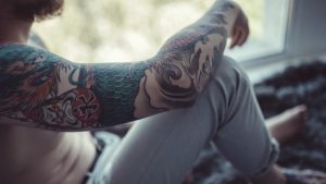 άνδρας με τατού κάθεται στεναχωρημένος στο τζάμι