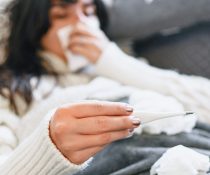 γυναίκα με μακρά covid-19 ξαπλωμένη στο κρεββάτι με θερμόμετρο