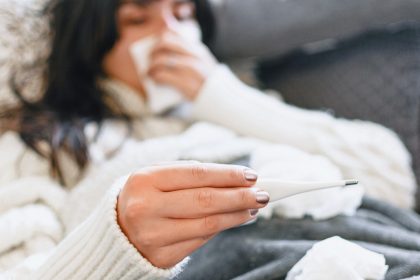 γυναίκα με μακρά covid-19 ξαπλωμένη στο κρεββάτι με θερμόμετρο