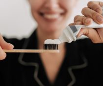 γυναίκα κρατάει οδοντόβουρτσα και διατηρεί την υγεία των ούλων