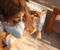 ναυτία πριν την περίοδο γυναίκα κάθεται στον καναπέ με ναυτία
