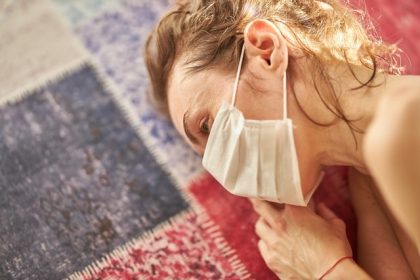 ψυχολογικά προβλήματα πανδημία γυναίκα με μάσκα ξαπλώνει στο πάτωμα